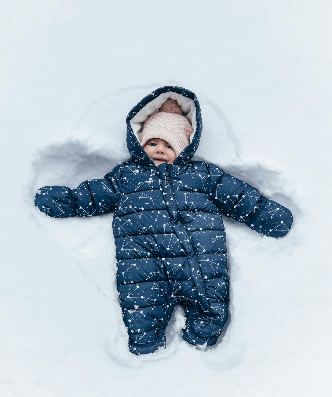 baby in snowsuit lying in snow